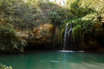 Long exposure waterfall during the day. green forest and rocky mountain. summer time. crystal clear blue water. beautiful waterfall with blue lake in the forest.