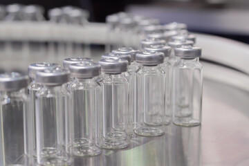 Conveyor belt with empty medical injection glass vials - pharmaceutical automatic production line. Pharmaceutical industry, manufacturing, medicine and automated pharma technology equipment concept