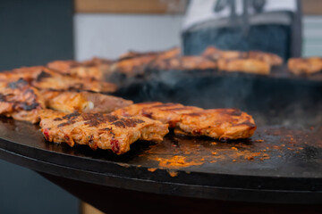 Process of cooking fresh juicy meat steaks on brazier at summer local food market - close up view. Outdoor cooking, gastronomy, barbecue, cookery and street food concept