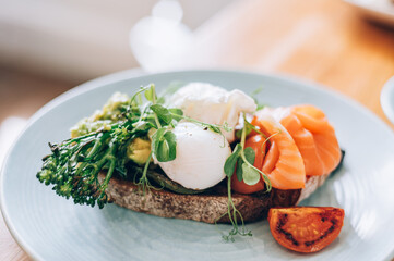 Healthy breakfast from poached eggs, steamed broccolli, salmon, smashed avocado, grilled mushrooms and tomato on toast