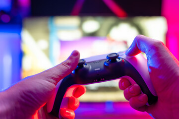 Modern gamepad in the hands of a gamer. The concept is video games, hobby, recreation, communications, game strategy, gaming. Technological background. Neon lighting.