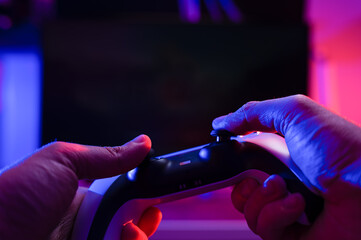 A gamer holds a joystick in his hands on a black background. Concept - modern gadgets, electronics, digital technologies. Communication with friends online, virtual reality.