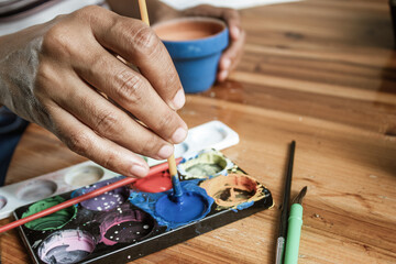 Hands of a Latin woman, painting clay pots to plant succulent plants