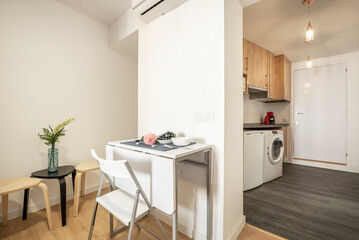 Studio apartment with open plan kitchen, living room with white wooden folding dining table and matching chairs
