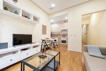 Apartment with open kitchen, living room with square dining table, side tables and light hardwood floors