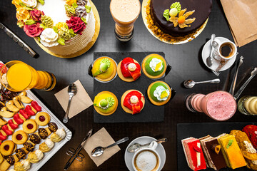 Set of desserts and cake on a black table, cream chocolate, icing sugar, butter croissants, orange...