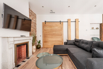 Living room with white marble fireplace, wall-mounted TV, wooden sliding door on rails and sofa...
