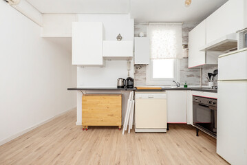 Kitchen with white cabinets without handles and a folding wooden table under the countertop