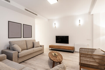Apartment with raw wood side tables, two three-seater sofas and a wooden sideboard with a TV