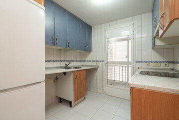 Apartment kitchen with blue furniture on top and wooden furniture on the bottom
