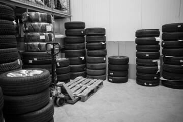 in a depot of a car repair shop there are many summer tires ready for a wheel change