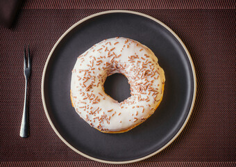 Tasty donuts insulated with white chocolate sprinkled with chocolate chips on a plate on a fine table. Fine pastries
