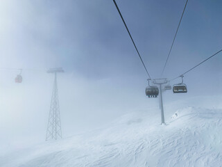 ski lift chairs in heavy fog on snowy mountains, bad weather, copy space - Powered by Adobe
