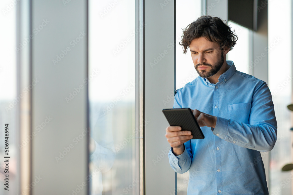 Poster portrait of focused man using digital tablet at office
