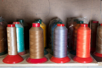 Close-up of multicolored spools of thread for the industrial sewing machine. Selective focus.