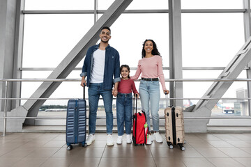 Fototapeta na wymiar Trip Together. Portrait Of Smiling Arab Family Of Three Posing At Airport