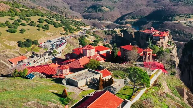 Kalambaka, Greece, Aerial view of monastery Varlaam and breathtaking pictures of valley and landmark canyon of Meteora at sunrise, Cradle on a ropeway, a lot of tourists, red roofs of monastery