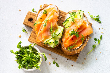 Open sandwich with cream cheese, salmon and cucumber. Top view at white table.