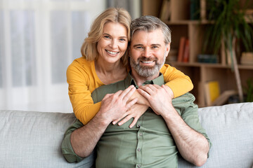 Portrait of beautiful smiling middle aged couple embracing at home