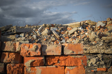 Fototapeta na wymiar Red selected bricks on the background of a destroyed building and blue sky