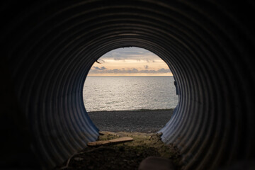 View from water drainage pipe on sea beach.