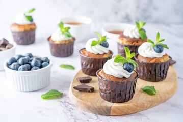 Chocolate cream cheese cupcakes with whipped cream, mint leaves and fresh blueberry