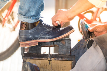 worker polishing a pair of black shoes on the street, a sunny day