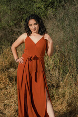 Obraz na płótnie Canvas Pretty Latina posing in orange dress in an autumn field