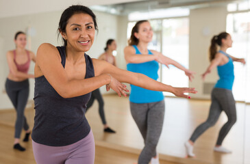 Fototapeta na wymiar Portrait of cheerful latin american woman exercising dance moves in fitness studio