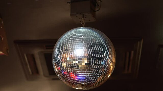 A rotating and sparkling disco ball on the ceiling in a dark room.