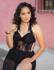 Young woman posing in sexy black dress on the street with high heels