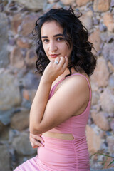 Fototapeta premium Pretty dark haired woman posing in short pink dress in urban eviroments