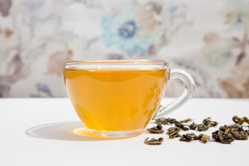Hot cup of green tea with dry tealeaf on the table	
