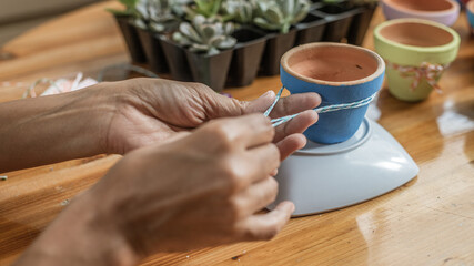 Hands of a Latin woman, painting clay pots to plant succulent plants