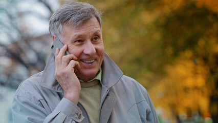 Portrait mature elderly man pensioner communicate remotely using modern smartphone talking family...