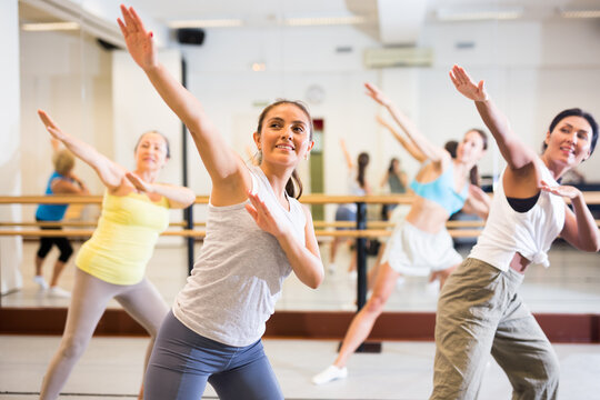 Positive women practicing vigorous dance movements in group dance class