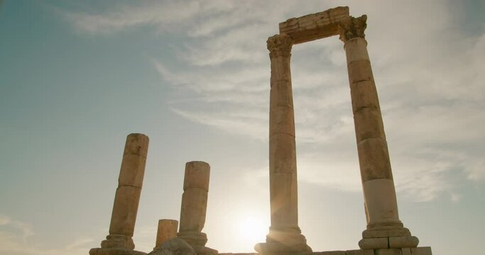 Amman Citadel - landmark archeological site in downtown Amman, capital of Jordan, Middle East. Ruins of Temple of Hercules - ancient roman architecture. 4K low angle wide shot with sun flare