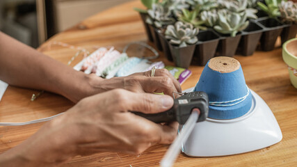 Hands of a Latin woman, painting clay pots to plant succulent plants