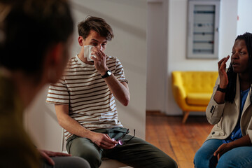 Young man in emotional distress at group therapy