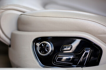 Buttons for adjusting seat position. White leather car seat and position adjustment button.