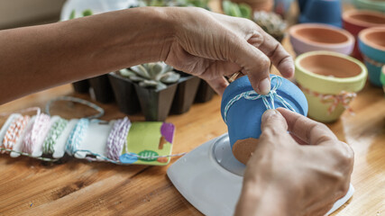 Fototapeta premium Hands of a Latin woman, painting clay pots to plant succulent plants