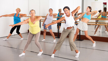 Fototapeta na wymiar Group of various aged women dancing modern dance in studio.