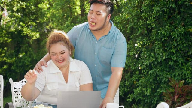 Fat Asian couple having fun to watch online movie on TV