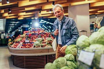 Mature man looking and choosing vegetables in supermarket