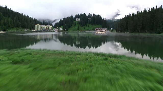 Drone view of Lago di Misurina, reflection of the mountain in the lake, flying through the fog in the Dolomites in Italy