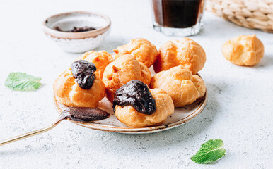 Delicious profiteroles with coffee on the table. Image with selective focus.
