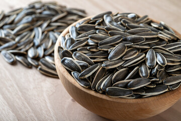 Black sunflower seeds in a bowl on wooden background