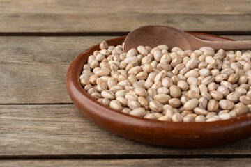 Brown beans in a plate over wooden table. Short depth of field