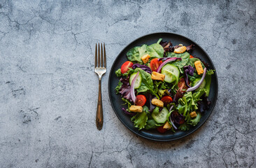 Top view of salad with lettuce, tomatoes and cucumbers on a plate.