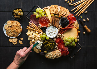 Hand over charcuterie board of meat, cheese, fruit, crackers.